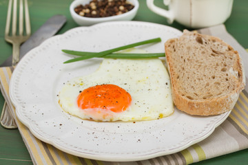 fried egg heart with onion and bread on white plate