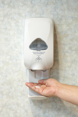 Person Using Wall Mounted Hand Sanitizer
