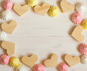 Frame made of wooden hearts and meringue pastel colors on a whit