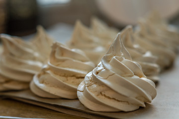 Creamy meringues on a parchment and blurred background
