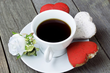 Romantic breakfast on Valentine's Day. Cup of coffee and heart shape cookies, white rose decoration, sticker for text. Toned image
