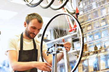 Laufradbau - Mechaniker zentriert Laufrad eines Fahrrades in der Werkstatt // Wheel building -...