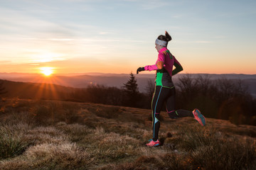 woman in colorful sportswear training for fitness in the sunset on the cold spring mountain trail