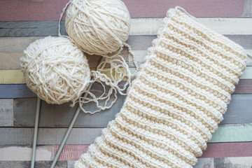 Balls of wool and knitting on a wooden table.