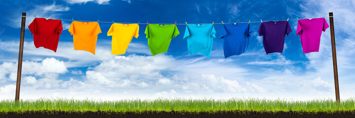 row of colorful shirts on meadow in front of blue sky