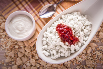 Fototapeta na wymiar Cottage cheese with jam on the background of scattered muesli.