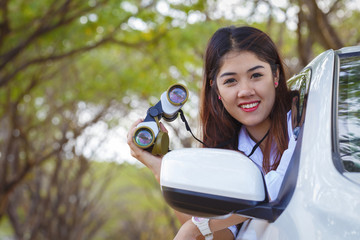 smiling asian girl holding binocular on the car