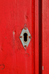 keyhole in rhombus form in an old red door