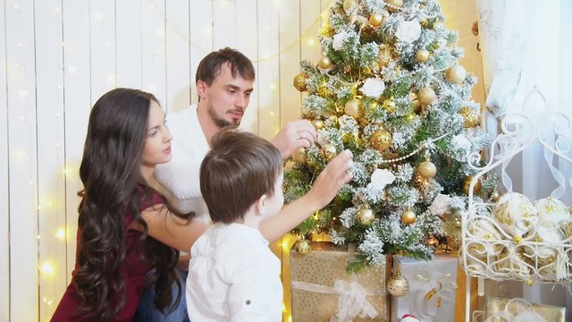 Family decorating a Christmas tree with boubles in the living-room