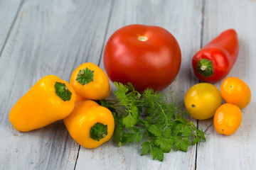 Mixed fresh colored vegetables, cherry tomatoes, mini paprika, tomato and fresh herbs on a wooden background