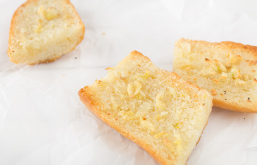 pieces of garlic bread made with baguette on white paper
