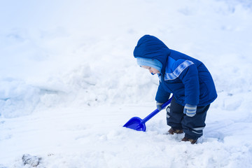 Fototapeta na wymiar Cute baby boy playing with snow toy shovel