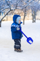 Cute baby boy playing with snow toy shovel