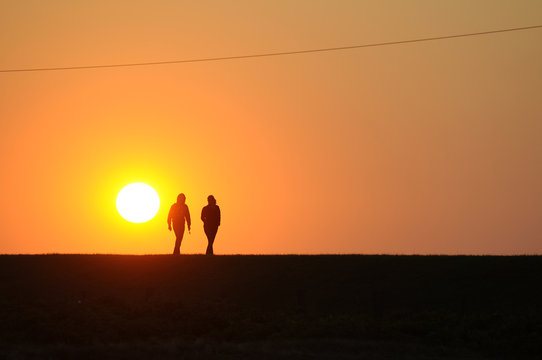 Zwei Menschen spazieren im Licht der untergehenden Sonne