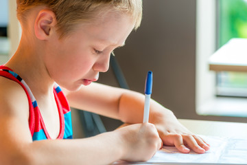 concentrated boy draws a pen on paper