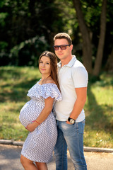 pregnant woman and her husband outdoors near the tree