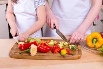 Obraz na płótnie Canvas mother teaching daughter to cut vegetables