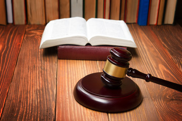 Law book with wooden judges gavel on table in a courtroom or law enforcement office.