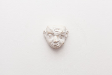 white plaster figurine on a white wall showing emotions