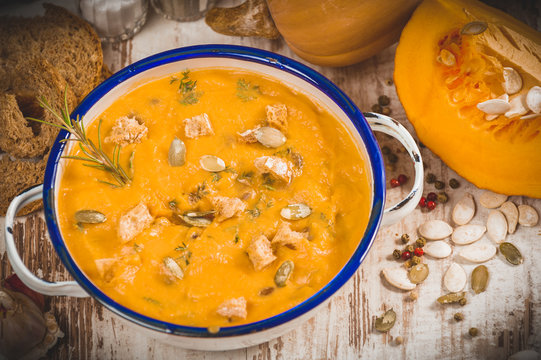 Homemade pumpkin soup in a tin bowl on rustic table
