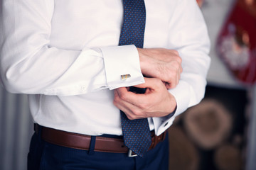 the man clasps cuff links on a shirt