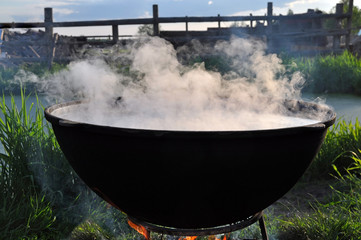 The big black cauldron on the fire with steam