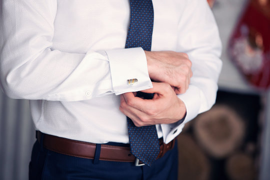 the man clasps cuff links on a shirt