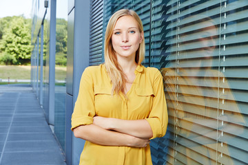 Zufriedene junge Geschäftsfrau vor Büro