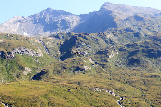 Transport helicopter flying with supplies and mountain panorama in Hohe Tauern Alps, Austria