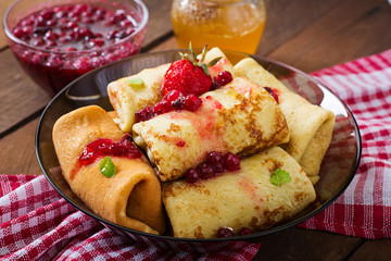 Golden pancakes with cranberry jam and honey in a rustic style.