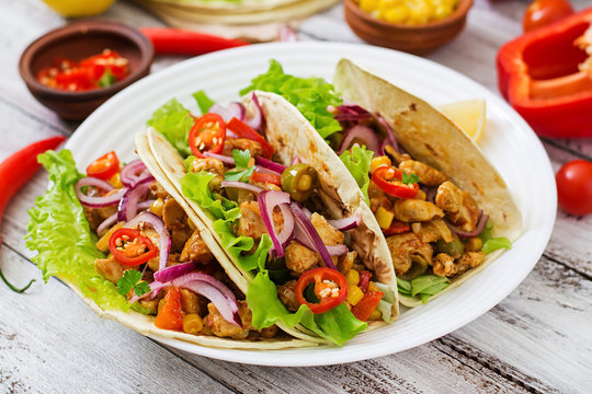 Mexican tacos with meat, corn and olives on wooden background.
