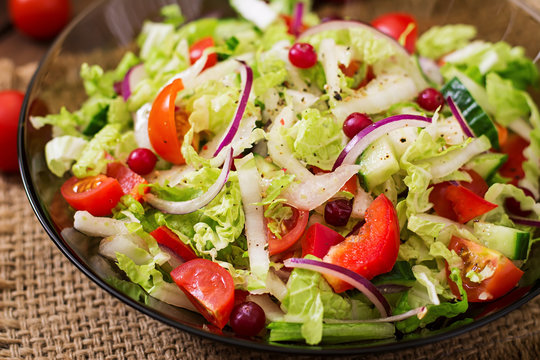 Dietary salad with fresh vegetables (tomato, cucumber, Chinese cabbage, red onion and cranberries)