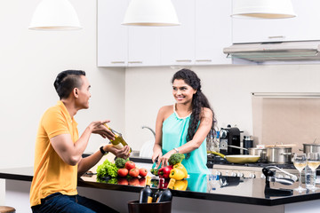 Indian woman and man in kitchen with red wine