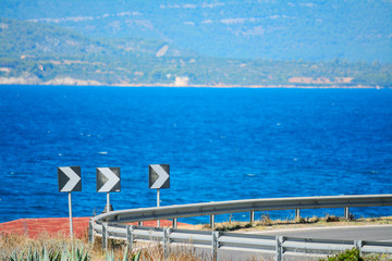 curve road signs by the sea in Alghero