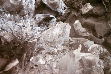 Beautiful big piece of ice with abstract cracks. Icicle bellow waterfall, stony and messy stream bank