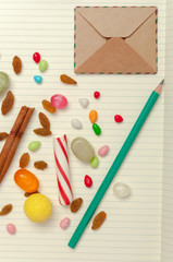 Candies, raisins, cinnamon, pencil and envelope at pages of note