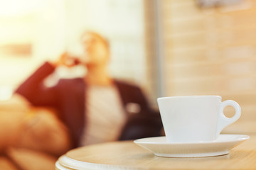 Cup of coffee with business man in the background out of focus