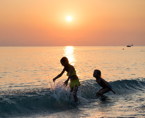 Silhouette of two young girl jumping in sea
