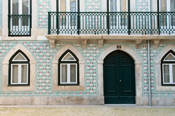 Fototapeta na wymiar Portuguese house with balcony and windows decorated with traditional multicolor portugal ceramics -azulejo. Lisbon, Portugal.