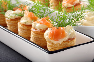 Appetizer puff pastry with dill dip and salmon on stone tray