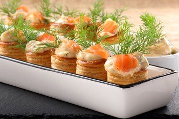 Appetizer puff pastry with dill dip and salmon on stone tray