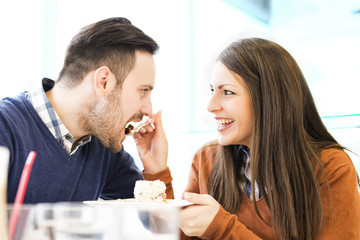 Young couple in love sitting in a cafe,eating cake