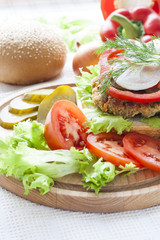 Homemade hamburger, vegetables and herbs.
Homemade hamburger, sliced tomatoes, onion, pepper, lettuce and dill on wooden board.