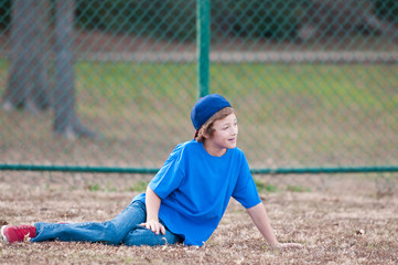 Obraz premium Young boy with baseball hat sitting in grass