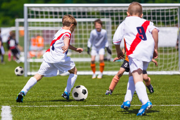 Training and football match between youth soccer teams. Young boys playing soccer game. Hard competition between players running and kicking soccer ball. Final game of football tournament for kids.