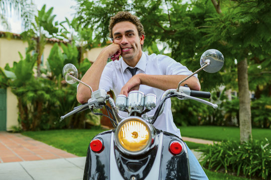 Hispanic businessman sitting on moped outdoors