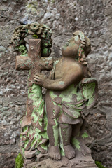 Fototapeta na wymiar Angel with a cross covered with moss
