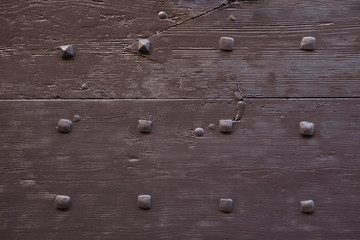 Brown painted wooden gate fixed with rivets. Background texture