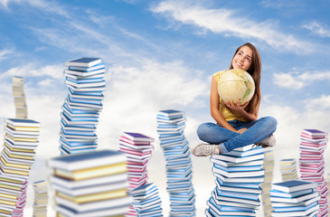pretty young student holding a earth globe sitting on a big book