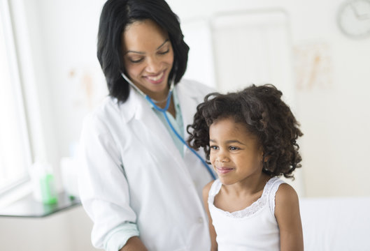 African American girl receiving checkup from doctor